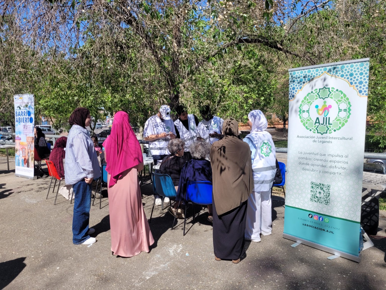 Personas reunidas al aire libre junto a un puesto de participación asociativa.